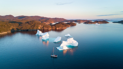 Air view to icebergs and yacht. Amazing Greenland.