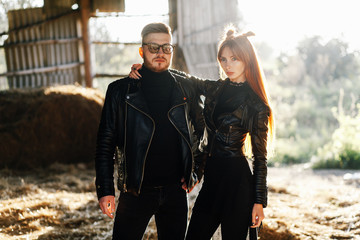 bearded guy hugging with a red-haired girl at sunset. Loving Couple dressed in leather jackets