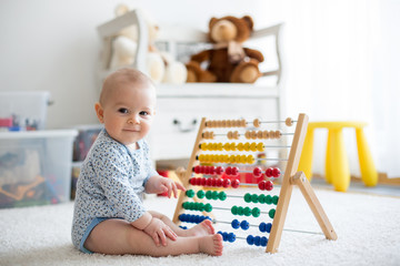 Cute little baby boy, playing with abacus at home