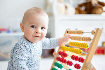 Cute little baby boy, playing with abacus at home