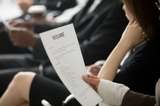 Multiracial business people waiting in queue sitting in row holding smartphones and cvs, diverse unemployed men and women preparing for job interview, human resources, employment and hiring concept
