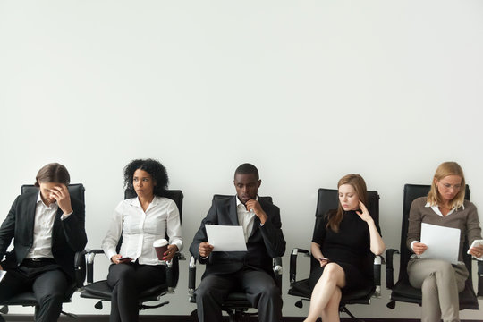 Rivalry at job interview concept, applicant walking in room while envious curious multiracial people sitting in row looking at rival waiting for result, winner and loser, jealous of other success