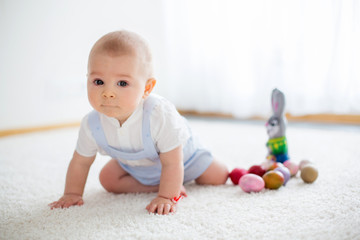 Cute little toddler child, baby boy, in sunny living room playing with  Easter chocolate bunny