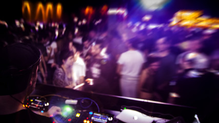DJ with headphone and dj set at night club party. People at the party are having fun on the...