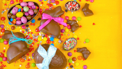 Fototapeta na wymiar Happy Easter overhead with chocolate Easter eggs and decorations on a wood table background with copy space.