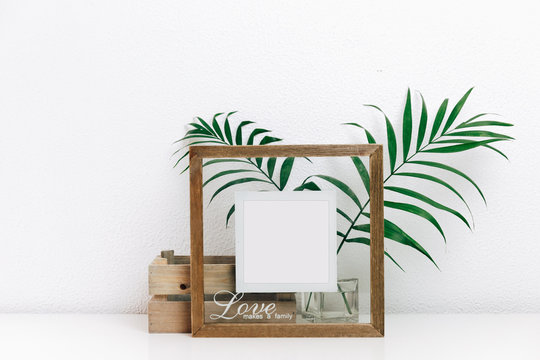 Mock up wooden frame with green tropical leaves. Nordic decorations, Scandinavian interior