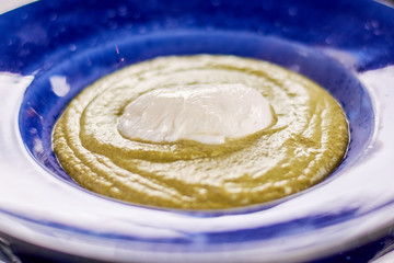Homemade cream soup with spinach and celery. Appetizing vegetarian cream soup. Spinach and celery cream soup in blue plate.