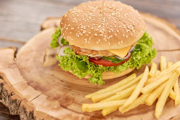 Delicious cheeseburger with fresh vegetables. Still life with traditional burger and french fries. Classic american food.