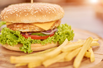 Close up of hamburger and french fries. Delicious burger with fresh chicken and vegetables. Still life with traditional burger and french fries.