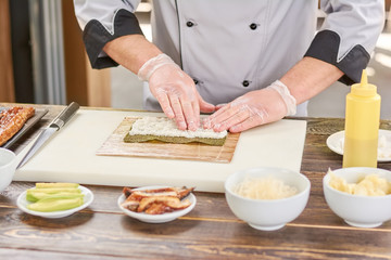 Chef hands touching white rice. Chef at professional kitchen preparing sushi roll. Japanese cook at work, kitchen.