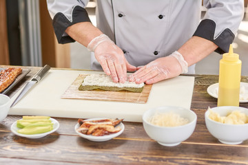 Obraz na płótnie Canvas Chef hands touching white rice. Chef at professional kitchen preparing sushi roll. Japanese cook at work, kitchen.