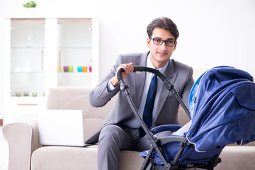 Businessman looking after newborn baby at home and teleworking
