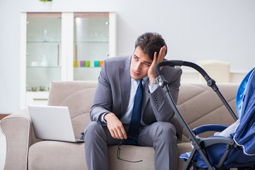 Businessman looking after newborn baby at home and teleworking