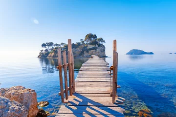 Papier Peint photo Lavable Île Greece. Picturesque wooden pedestrian Bridge to the small atoll island, view from great Greek Zante or Zakinthos island. Beautiful morning scenery in sunny spring day.