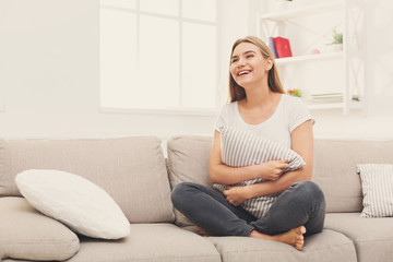 Obraz premium Young smiling woman sitting on beige couch
