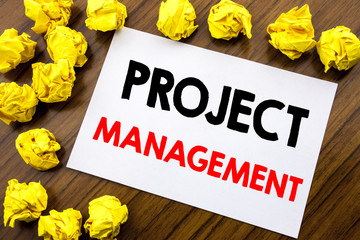 Fototapeta premium Handwritten text showing word Project Management. Business concept writing Strategy Plan Goals Written on sticky note paper, wooden background with space office view with folded yellow paper