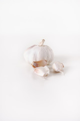 Whole, large garlic bulb or head with three unpeeled garlic cloves in front on white background