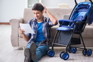 Young father assembling baby pram at home