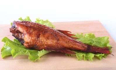 Smoked fish and lemon on green lettuce leaves on Wooden cutting board isolated on white background.