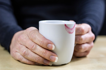 Empty white mug with gloves. Hands in warm gloves holding a china mug on a wooden kitchen table.