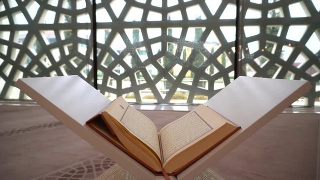 A man is reading Quran on the reading desk in a mosque.