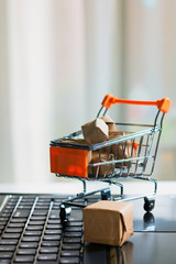 Online shopping concept. Shopping cart, small boxes, laptop on the desk