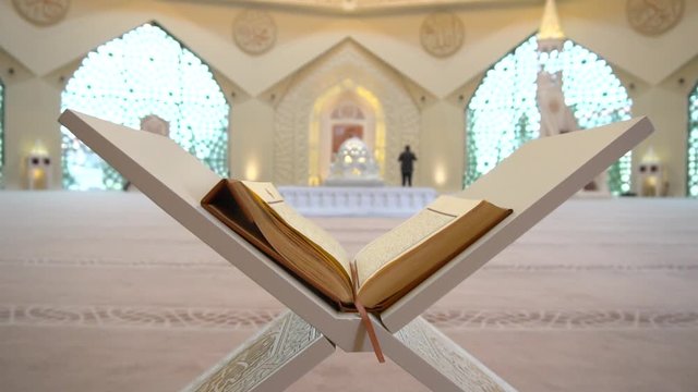 A man is reading Quran on the reading desk in a mosque.