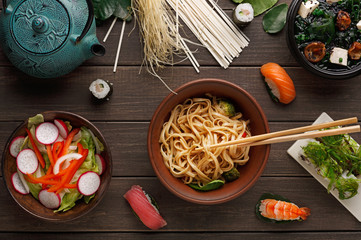 Bowl of rice noodles with soy souce on wooden background