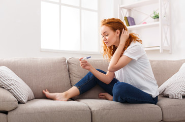 Young worried woman with recent pregnancy test