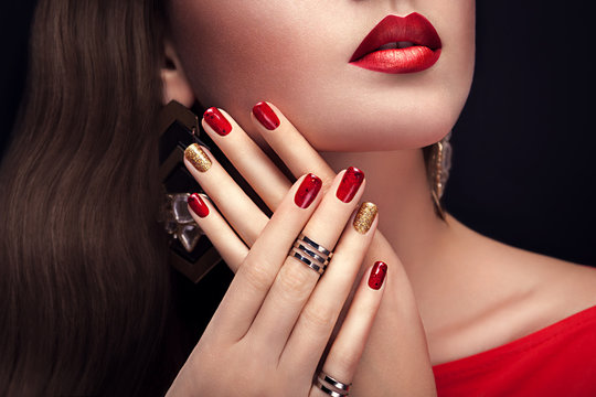 Beautiful woman with perfect make-up and red and golden manicure wearing jewellery