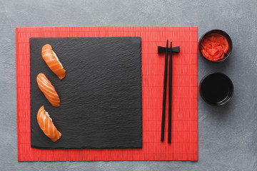 Sushi set and chopsticks on red mat, top view