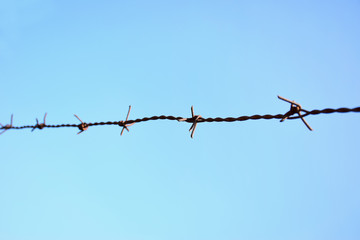Close up of barbed wire against the blue sky 