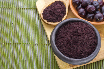 fruit and acai powder in bowl on wooden background