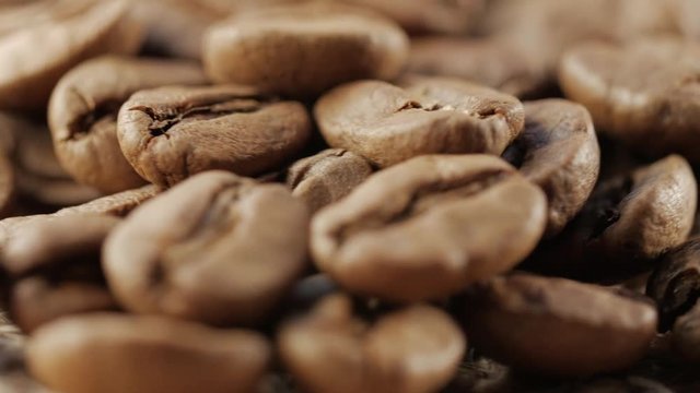 Slow rotation of the heap of coffee beans. Close up of coffee beans. Loopable rotation. In front of the camera rotates plate with coffee beans.