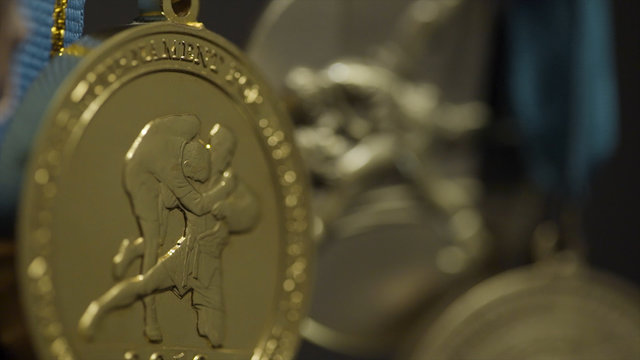 Close up of the golden medals. A rugged gold medal setup majestically against grey background. Gold medals before handing to champions. Gold, silver and bronze medals close up