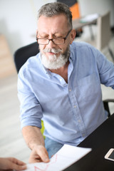 Fototapeta premium Senior man working with documents at table in office