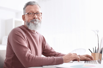 Fototapeta premium Senior man working with laptop at table in office