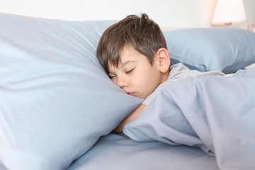 Cute little boy sleeping in bed at home