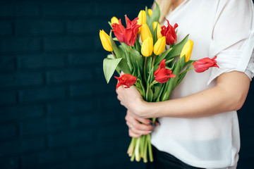 yellow and pink tulips girl holding hands on black background