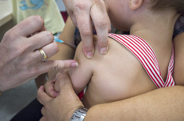 Mature nurse vaccinating a little boy