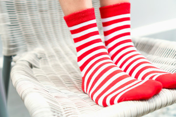 Legs in socks red colors alternate, white side stand on white chair.