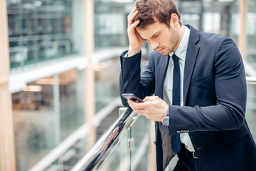 Bad news. Worried businessman Read text on mobile phone