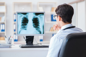 Rear view of doctor looking at x-ray on computer