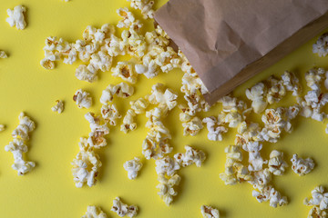 Popcorn in paper bag on yellow, top view