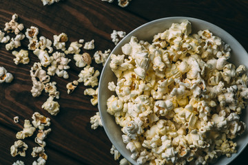 Popcorn in plate on wooden table, top view
