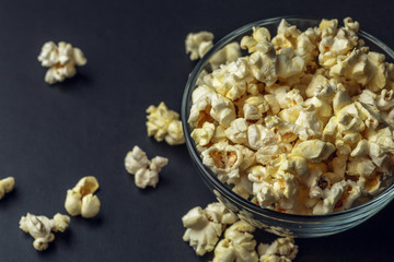 Popcorn in glass bowl on dark background, copy space