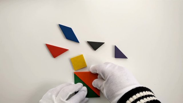 man playing wooden tangram and shaping it like a burning candle on white