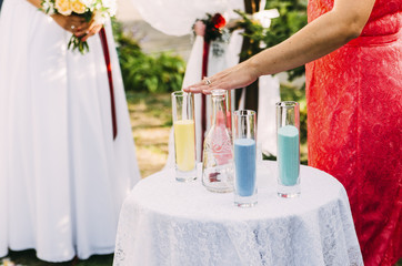 wedding couple with colored sand in the park with bottles and glasses on the table