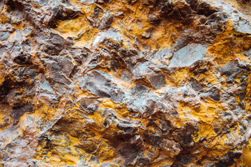 Macro closeup of black and yellow stone on a wall