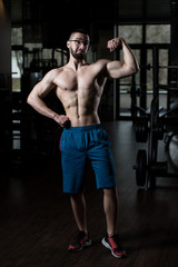Naklejka na ściany i meble Muscular Man Flexing Muscles In Gym